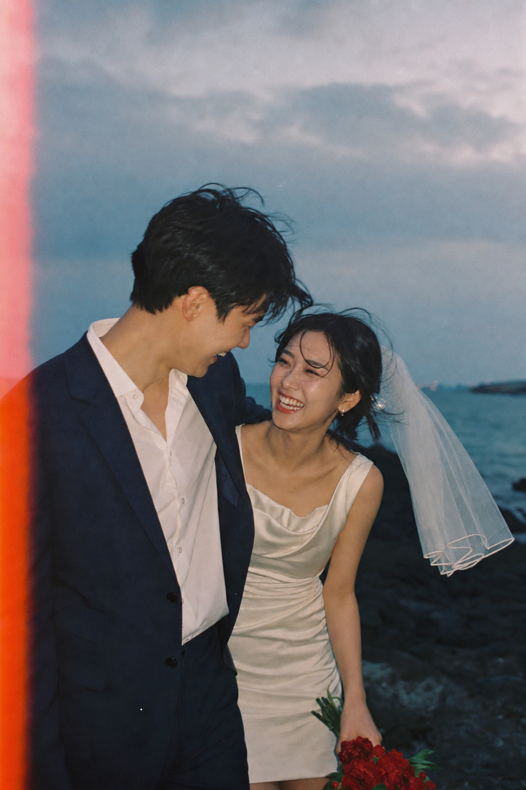 해안가에서 촬영한 신랑 신부의 가로 화보 컷